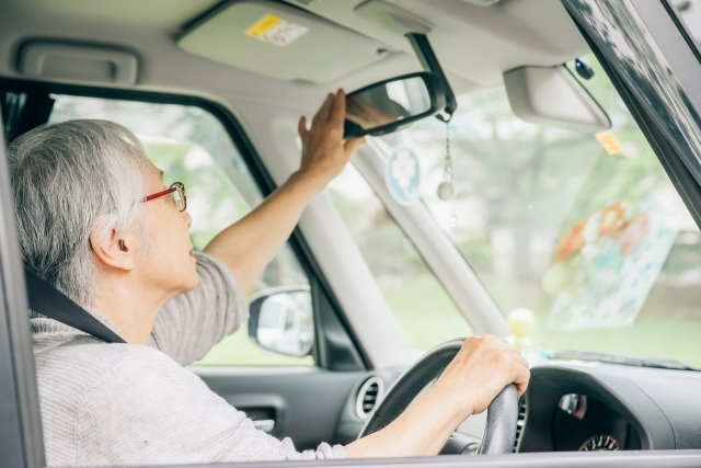 老人が車のミラーを直している様子