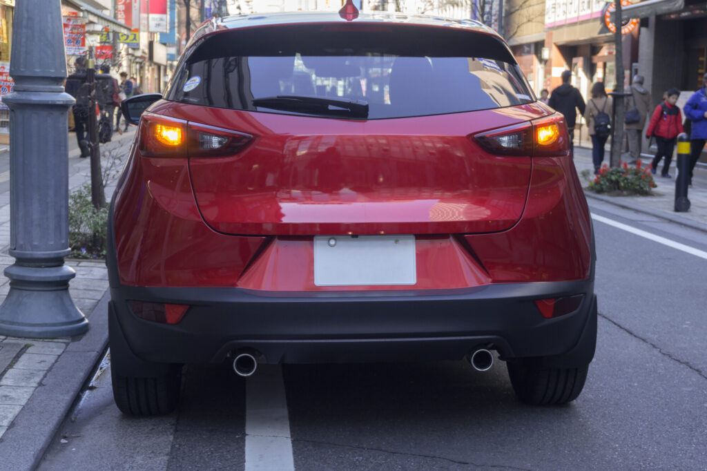 赤い停車中の車がハザードランプを点けている様子