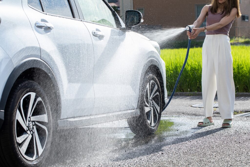水で車（白）の汚れを洗い流す様子