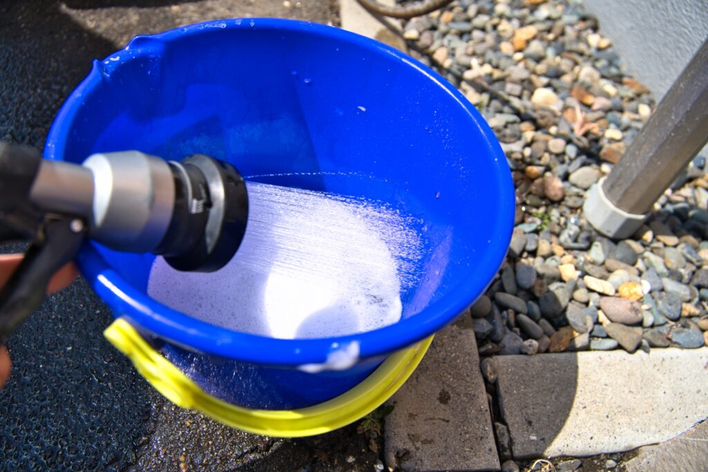 バケツに入れたカーシャンプーを泡立てる様子