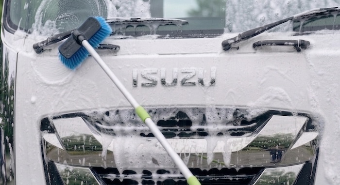 持ち手が長い洗車ブラシでトラックを洗車している様子