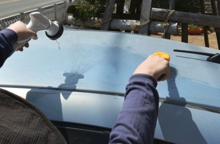 青い車の屋根を手洗い洗車している様子