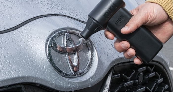 ブロワーでエンブレムの隙間の水滴を飛ばしている様子