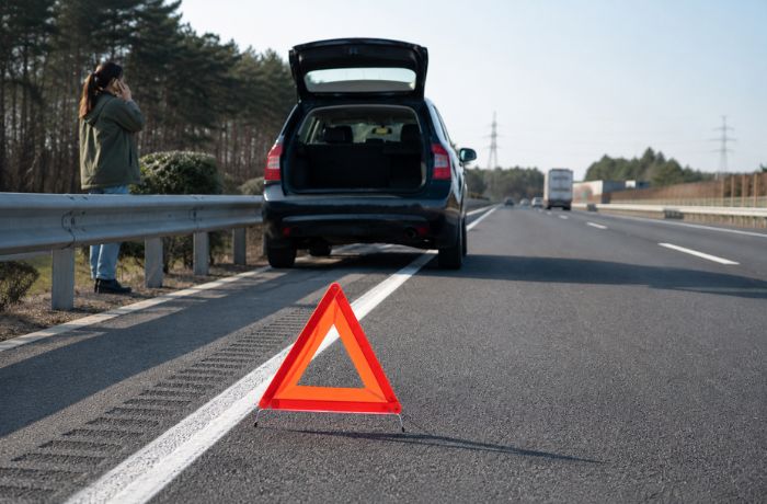 高速道路上で三角表示板を表示し、救助依頼をしている写真