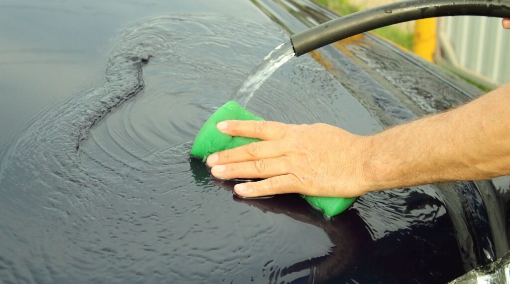 車のボンネットに水をかけて洗車している様子